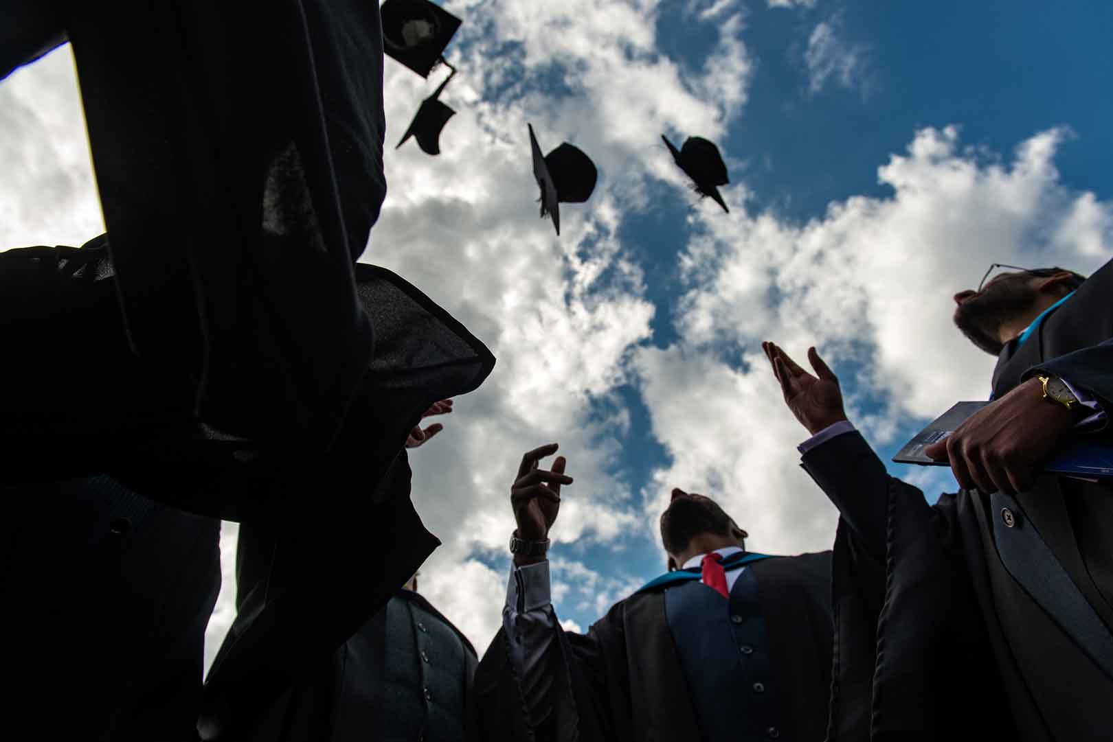 Graduates throwing caps into blue sky